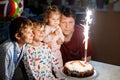 Adorable happy little kid boy celebrating his birthday. Child blowing candles on cake. Father, brother and baby sister Royalty Free Stock Photo