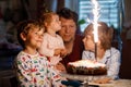 Adorable happy little kid boy celebrating his birthday. Child blowing candles on cake. Father, brother and baby sister Royalty Free Stock Photo