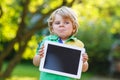 Adorable happy little kid boy holding tablet pc, outdoors Royalty Free Stock Photo