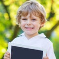 Adorable happy little kid boy holding tablet pc, outdoors Royalty Free Stock Photo