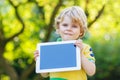 Adorable happy little kid boy holding tablet pc, outdoors Royalty Free Stock Photo