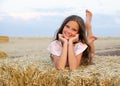 Adorable happy smiling ittle girl child lying on a hay rolls in a wheat field Royalty Free Stock Photo