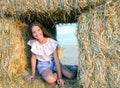 Adorable happy smiling ittle girl child sitting on a hay rolls in a wheat field Royalty Free Stock Photo