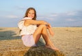 Adorable happy smiling ittle girl child sitting on a hay rolls in a wheat field Royalty Free Stock Photo