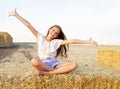 Adorable happy smiling ittle girl child sitting on a hay rolls in a wheat field Royalty Free Stock Photo