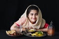 Adorable happy smiling Muslim girl with beautiful eyes wearing hijab and traditional costume sitting at kitchen table, portrait of Royalty Free Stock Photo