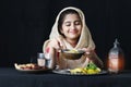 Adorable happy smiling Muslim girl with beautiful eyes wearing traditional hijab, sitting at kitchen table, portrait of kid Royalty Free Stock Photo