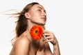 Adorable happy smiling woman with bared shoulders and blonde long hair holding orange gerbera daisy flower over white Royalty Free Stock Photo