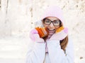 Adorable happy young blonde woman in pink knitted hat scarf having fun drinking hot tea from mug snowy winter park forest in natur Royalty Free Stock Photo