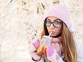 Adorable happy young blonde woman in pink knitted hat scarf having fun drinking hot tea from mug snowy winter park forest in natur Royalty Free Stock Photo