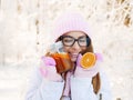 Adorable happy young blonde woman in pink knitted hat scarf having fun drinking hot tea from mug snowy winter park forest in natur Royalty Free Stock Photo