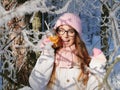 Adorable happy young blonde woman in pink knitted hat scarf having fun drinking hot tea from mug snowy winter park forest in natur Royalty Free Stock Photo