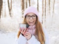 Adorable happy young blonde woman in pink knitted hat scarf having fun drinking hot tea from thermos cup snowy winter park forest Royalty Free Stock Photo