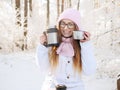 Adorable happy young blonde woman in pink knitted hat scarf having fun drinking hot tea from thermos cup snowy winter park forest Royalty Free Stock Photo