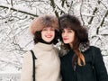 Adorable happy young brunette women girlfriends in fur hats having fun snowy winter park forest in nature Royalty Free Stock Photo