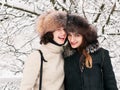 Adorable happy young brunette women girlfriends in fur hats having fun snowy winter park forest in nature Royalty Free Stock Photo