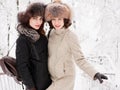 Adorable happy young brunette women holding hands in fur hat having fun snowy winter park forest in nature Royalty Free Stock Photo