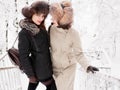 Adorable happy young brunette women holding hands in fur hat having fun snowy winter park forest in nature Royalty Free Stock Photo