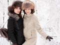 Adorable happy young brunette women holding hands in fur hat having fun snowy winter park forest in nature Royalty Free Stock Photo