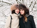 Adorable happy young brunette women girlfriends in fur hats having fun snowy winter park forest in nature Royalty Free Stock Photo