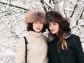 Adorable happy young brunette women girlfriends in fur hats having fun snowy winter park forest in nature Royalty Free Stock Photo