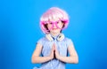 Adorable headset user with praying hands. Small child wearing adjustable white headset and pink hair wig. Little girl Royalty Free Stock Photo
