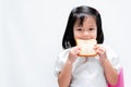 Adorable healthy little girl holding a white bread in front of her face. A hungry child is about to bite into a loaf of bread.