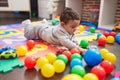 Adorable hispanic baby playing with balls lying on floor at kindergarten Royalty Free Stock Photo