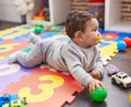 Adorable hispanic baby playing with balls lying on floor at kindergarten Royalty Free Stock Photo