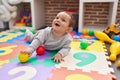 Adorable hispanic baby playing with balls lying on floor at kindergarten Royalty Free Stock Photo
