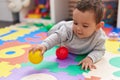 Adorable hispanic baby playing with balls lying on floor at kindergarten Royalty Free Stock Photo