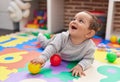 Adorable hispanic baby playing with balls lying on floor at kindergarten Royalty Free Stock Photo