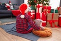 Adorable hispanic boy hugging teddy bear sitting on floor by christmas tree at home Royalty Free Stock Photo