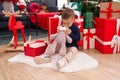 Adorable hispanic boy kissing teddy bear sitting on floor by christmas tree at home Royalty Free Stock Photo