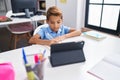 Adorable hispanic boy student sitting on table doing homework at classroom Royalty Free Stock Photo