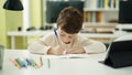 Adorable hispanic boy student sitting on table doing homework at classroom Royalty Free Stock Photo