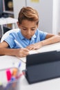 Adorable hispanic boy student sitting on table doing homework at classroom Royalty Free Stock Photo