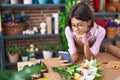 Adorable hispanic girl florist smiling confident using smartphone at flower shop Royalty Free Stock Photo