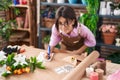 Adorable hispanic girl florist smiling confident writing on notebook at flower shop Royalty Free Stock Photo