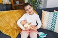 Adorable hispanic girl playing with baby doll sitting on sofa at home Royalty Free Stock Photo