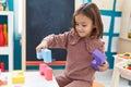 Adorable hispanic girl playing with construction blocks sitting on chair at kindergarten