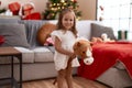Adorable hispanic girl playing with horse toy standing by christmas tree at home Royalty Free Stock Photo