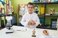 Adorable hispanic girl scientist student holding brain at laboratory classroom