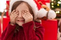 Adorable hispanic girl sitting on floor by christmas tree with eyes closed at home Royalty Free Stock Photo