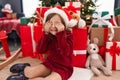 Adorable hispanic girl sitting on floor by christmas tree with eyes closed at home Royalty Free Stock Photo