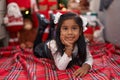 Adorable hispanic girl smiling confident lying on floor by christmas tree at home Royalty Free Stock Photo