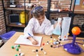 Adorable hispanic girl student holding test tube writing on notebook at laboratory classroom Royalty Free Stock Photo