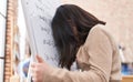 Adorable hispanic girl student solving maths exercise stressed with head on chalkboard at classroom