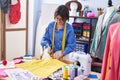 Adorable hispanic girl tailor smiling confident cutting cloth at clothing factory