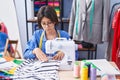 Adorable hispanic girl tailor using sewing machine at clothing factory